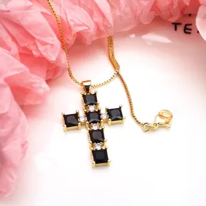 Close-up of a gold-plated copper cross pendant set with black square zircon stones and white gems
