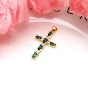 Detailed view of a gold-plated cross pendant with green and white marquise cut stones