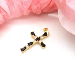 Detailed macro view of a gold-plated cross pendant with black and clear cubic zirconia