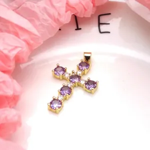 Macro view of gold-plated cross pendant featuring sparkling purple and white zircons.