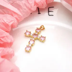 Detailed macro shot showing a gold-plated copper cross pendant with pink zircons