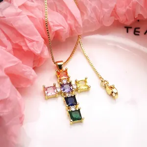 Close-up detail of a gold-plated cross necklace with vibrant square-cut cubic zirconia.