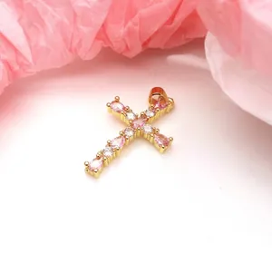 Detailed view of a gold cross pendant featuring sparkling pink and white zircons