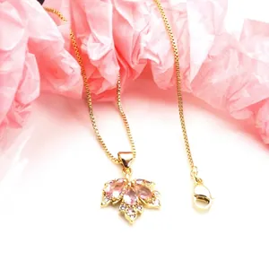 Close-up of a maple leaf pendant with pink micro-paved zircons and gold finish.