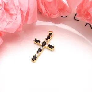 Detailed view of a gold-plated cross pendant featuring black and white cubic zirconia.