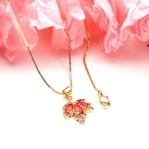 Close-up of a gold-plated maple leaf necklace with sparkling red micro-set zirconia