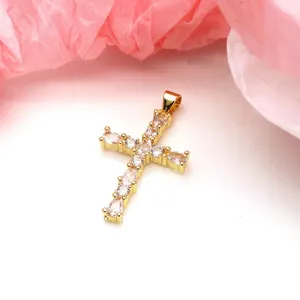 Macro view of a gold-plated cross pendant featuring sparkling pear-shaped zircons