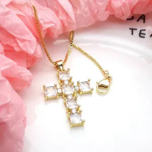 Close-up of a gold-plated cross pendant necklace featuring sparkling square zirconia