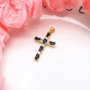 Detail of a copper cross pendant set with blue and white cubic zirconia stones.