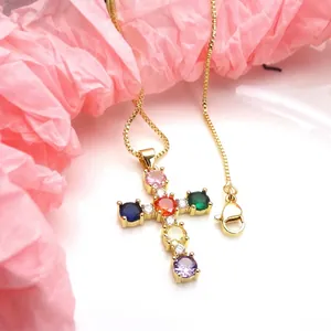 Close-up of gold-plated cross pendant with vibrant multi-colored cubic zirconia stones.
