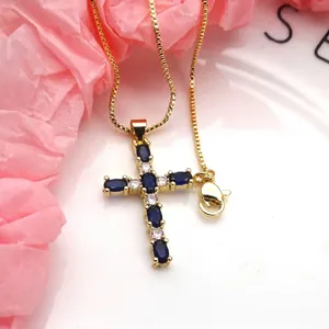 Close-up of gold-plated cross pendant featuring blue and white zirconia stones.