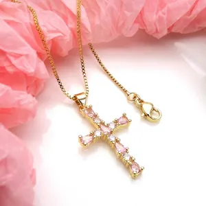 Close-up of gold cross pendant necklace with pink and clear cubic zirconia stones