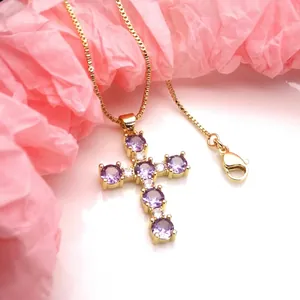 Close-up of golden cross pendant with purple round zircon crystals