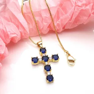 Detailed view of a gold cross pendant necklace featuring blue and white zirconia