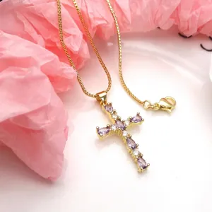 Close-up detail of a gold-plated cross pendant featuring purple and clear marquise zircons