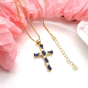 Detailed macro view of the gold cross pendant with blue and white cubic zirconia stones