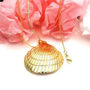 Close-up of elegant golden scallop shell pendant necklace on a pink floral backdrop