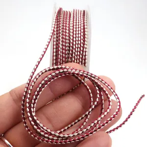 Detailed macro view of 1.5mm red and beige dragon pattern twisted cord held in hand