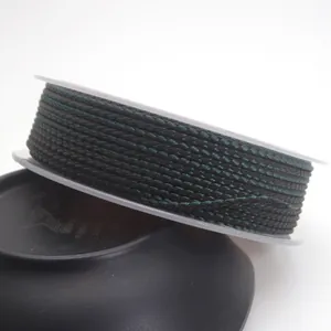 Macro view of 1.5mm dark green and black braided dragon pattern cord on a spool