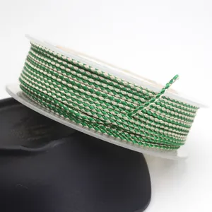 Close-up of 1.5mm green and beige dragon pattern braided cord on a spool for DIY jewelry