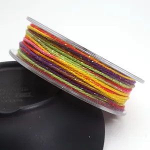 Close-up of 1.2mm multicolored cotton thread with gold glitter on transparent spool