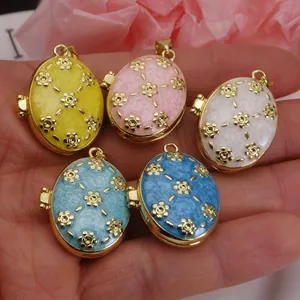 Close-up of enamel flower locket pendants in various colors held in hand