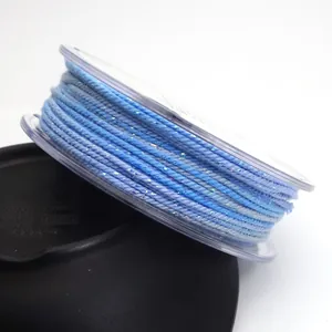 Detailed view of 1.2mm blue variegated braided cotton cord with glitter on clear spool
