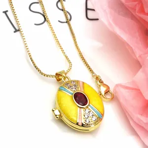 Detailed view of gold-plated oval enamel locket pendant with red stone and cubic zirconia
