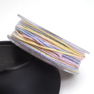 Macro detail of 1.2mm gradient cotton cord with gold flecks on a clear spool