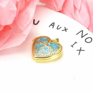 Macro detail of a gold-plated heart-shaped pendant with blue enamel and zircon inlay.