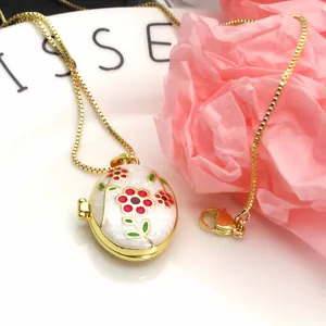 Close-up of gold-plated oval locket necklace with colorful enamel flower pendant
