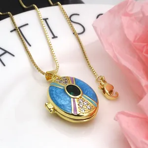 Close-up of gold-plated copper locket necklace with zircon and blue enamel details.