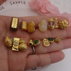 Close-up view of diverse gold-tone DIY jewelry beads with gourd and heart design motifs