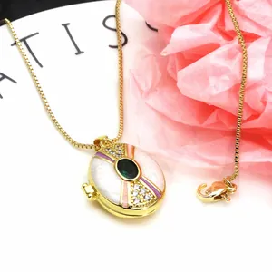 Close-up of gold-plated oval locket necklace with green gemstone and enamel detail