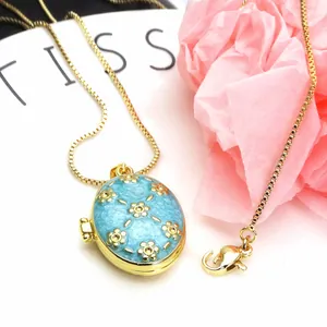 Close-up of a blue enamel locket pendant with gold flower patterns on a golden chain.