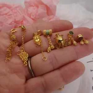 Macro detail view of assorted sand gold DIY jewelry charms featuring tassels and zircon