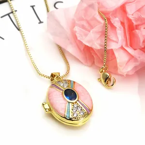 Detailed close-up of gold-plated oval locket necklace with blue zircon and pink enamel