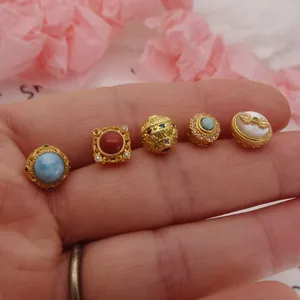 Detailed view of five vintage gold-plated DIY jewelry beads with colorful stone inlays