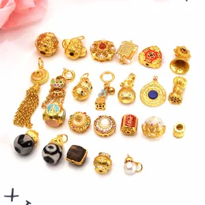 Assorted sand gold DIY jewelry charms with lotus, gourd, and dZi bead designs.