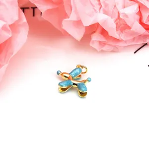 Close-up of a blue enamel balloon dog pendant with gold trim on pink textured background