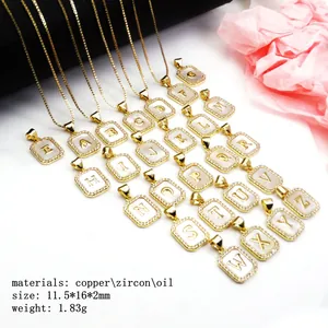 Close-up detail of gold-plated square initial pendants with shell inlay and cubic zircon halo