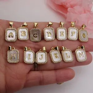 Close-up of rectangular shell initial pendants with gold-plated zirconia borders