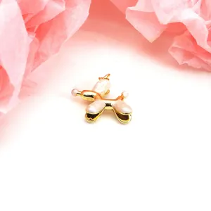 Macro detail view of a gold-plated balloon dog charm featuring pearly white enamel finish