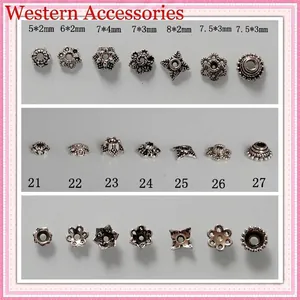 Vista detallada de capuchones de flores y espaciadores de plata tibetana para joyería DIY.