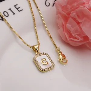 Close-up detail of gold letter C pendant with mother-of-pearl and sparkling zircons