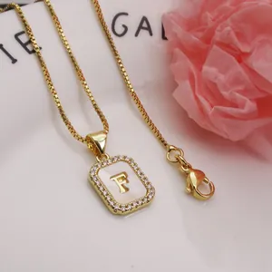 Macro detail view of a gold square pendant necklace featuring the letter F with zircons