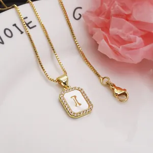 Close-up of a gold-plated necklace with a square shell pendant featuring the letter I