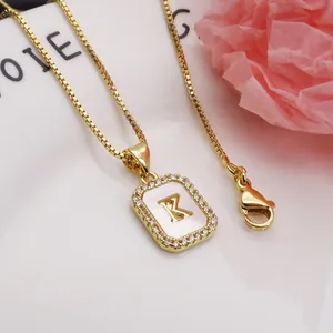Detail view of gold letter K pendant with shell inlay and zirconia embellishments.