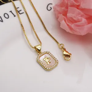 Detailed macro view of a gold-plated square pendant with initial P and shell inlay