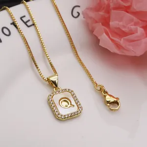 Detailed macro view of golden letter Q pendant with shell inlay and zirconia halo